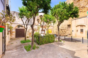A narrow street with stone buildings, trees, and a cobblestone path. - Unik Vacation Sant Joan (Tarragona)