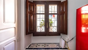Ein Zimmer mit Holztür, einem Fenster mit Blick auf die Straße und einem Fliesenboden.