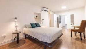 Ein modernes Schlafzimmer mit einem Bett, einem Sessel, einem kleinen Tisch und einer Klimaanlage.