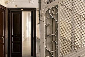 A hallway with a dark wooden door and a metal gate with decorative scrollwork.