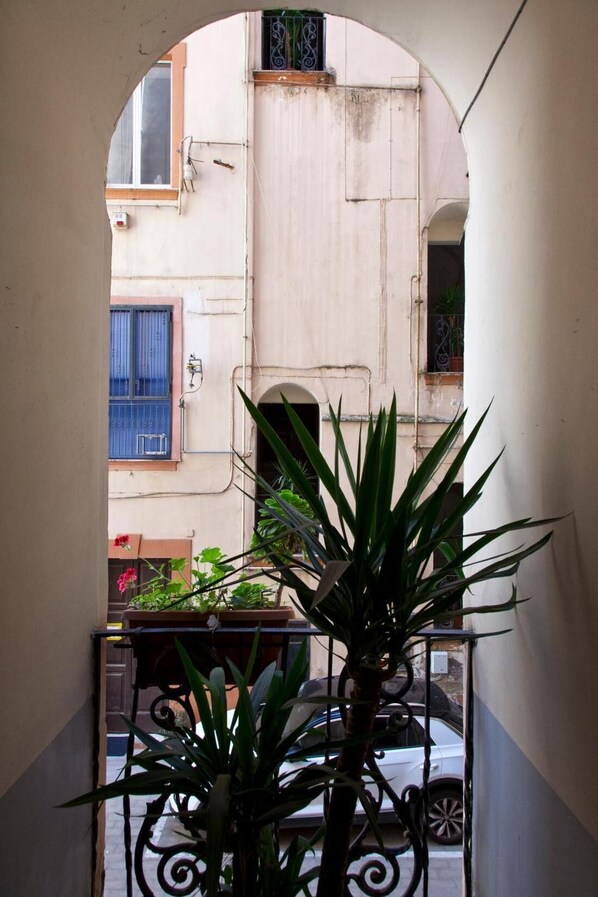An arched corridor with a view of a building's exterior, including a window with blue shutters and a door with a metal gate. - Archivio 32 Neapolitan Apartment (Naples)
