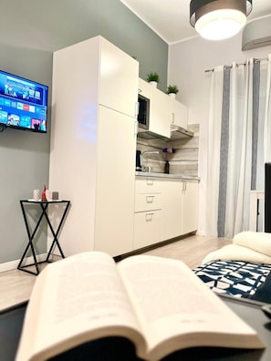 A modern living room with a flat-screen TV, a sofa, and a book on a table.