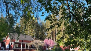 A red house with a porch, surrounded by green grass and trees. - Charming Property With Private Pool (Marsta)