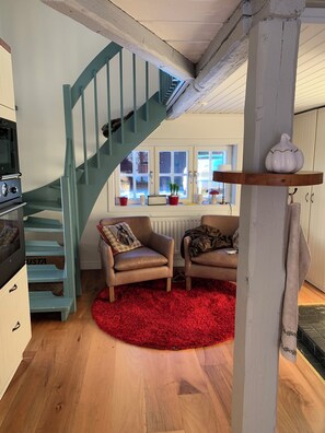 A cozy living area with a staircase, a red rug, and a kitchen with a stove. - Charming Property With Private Pool (Marsta)