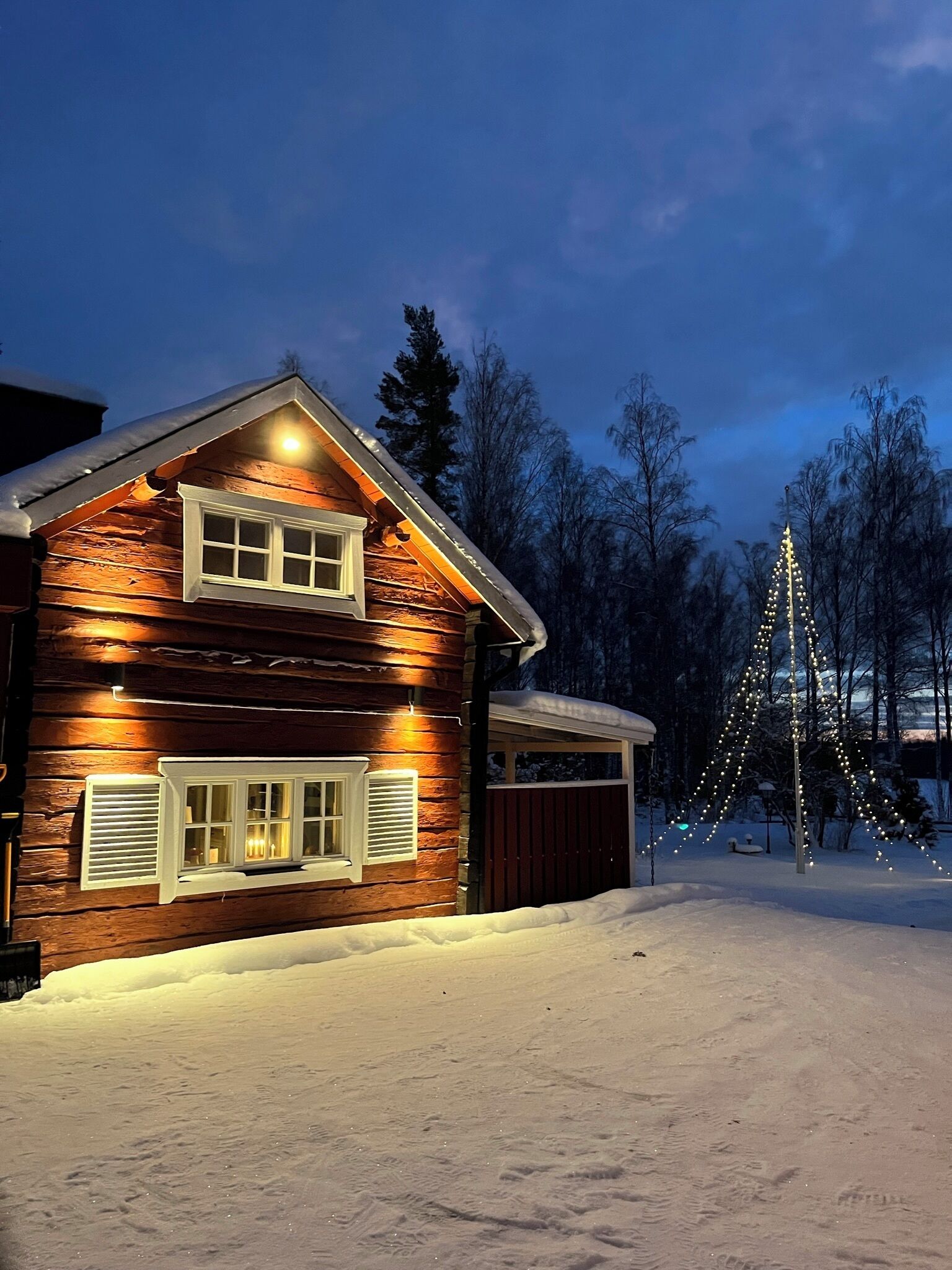 A log cabin with a garage and a snow-covered driveway.