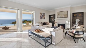 A spacious living room with a large window overlooking a scenic view, a fireplace, and a comfortable seating area. - The Bay Crest Manor Views Pool Beach (Mount Eliza)