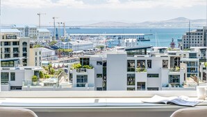 A modern room with a large window overlooking a marina and cityscape. - Charming Central Apartment Aquene bay (Cape Town)