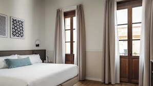 A hotel room with a large bed, wooden floor, and two windows with curtains. - BYPILLOW Sinfonía  (Valencia)