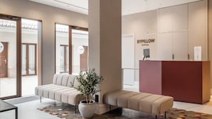 A modern lobby with a sofa, a reception desk, and a potted plant. - BYPILLOW Sinfonía  (Valencia)