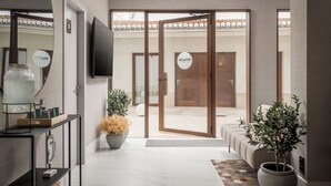 A modern hotel lobby with a reception desk, a television, and a large mirror. - BYPILLOW Sinfonía  (Valencia)
