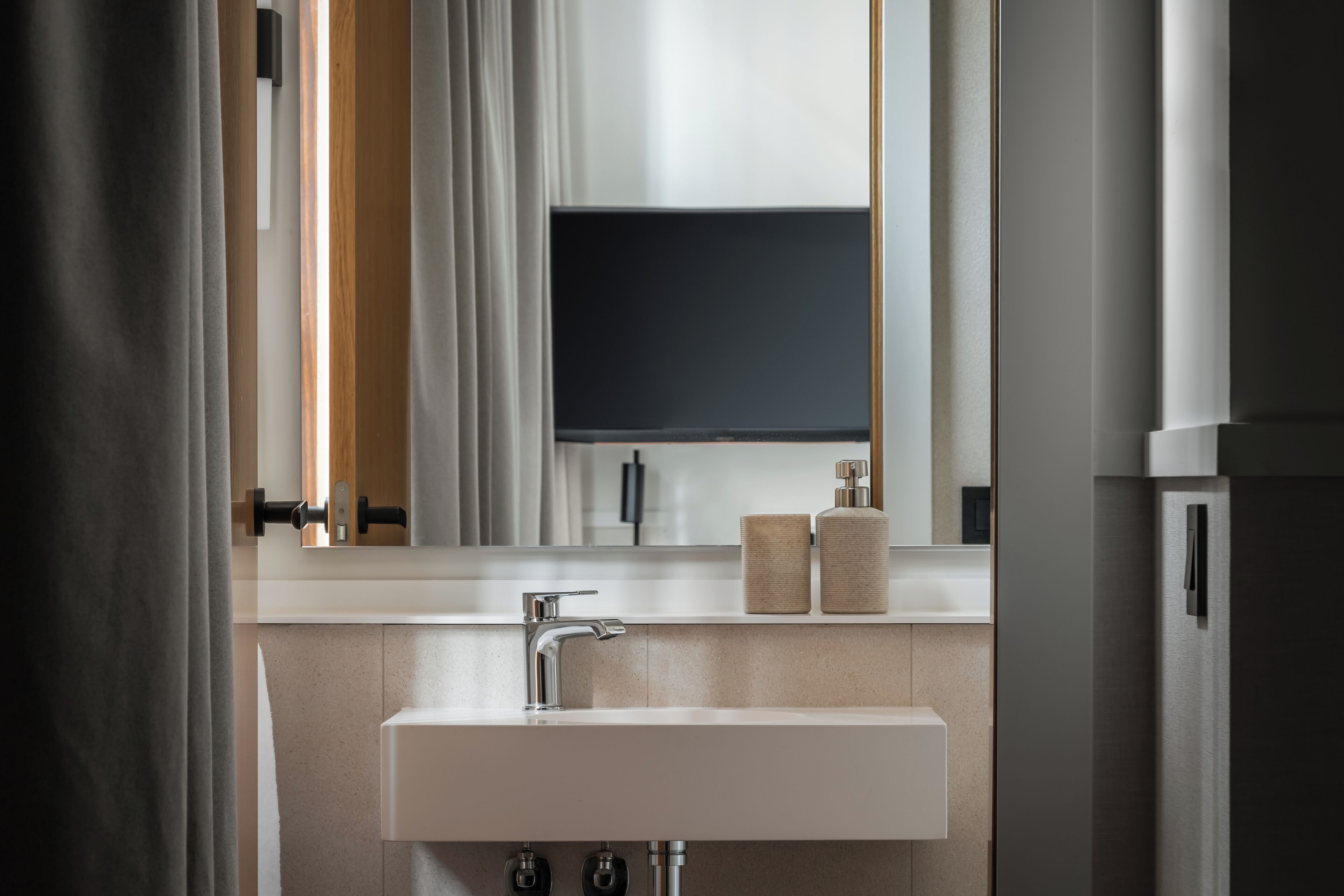 A modern bathroom with a white sink, a mirror, and a toilet.