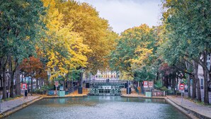 A canal with a bridge, surrounded by trees with autumn foliage. - Boho on the Boulevard, by Veeve (Paris)