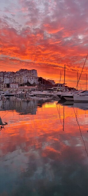 A marina with boats docked, a waterfront building, and a sunset sky. - B&B MARINA SLEEP AND SHIP (Rodi Garganico)