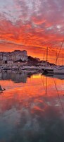Un puerto deportivo con barcos amarrados, un edificio frente al agua y un cielo al atardecer.