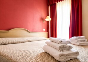A hotel room with a bed, a lamp, and a window with red curtains. - B&B MARINA SLEEP AND SHIP (Rodi Garganico)