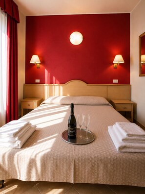 A hotel room with a bed, two bedside lamps, a bottle of Prosecco, two glasses, and towels. - B&B MARINA SLEEP AND SHIP (Rodi Garganico)