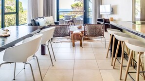 A modern kitchen with a bar area, large windows, and a view of the sea. - Delightful Rental w Sea Views Vadi Apartment (Cape Town)