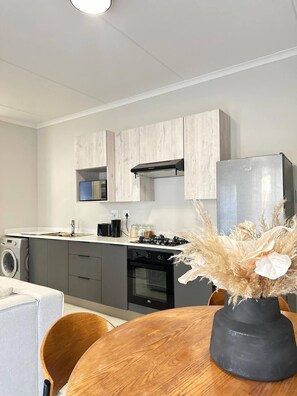 Een moderne keuken met grijze kastjes, een roestvrijstalen koelkast, een fornuis en een wasmachine.