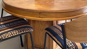 A round wooden dining table with a black vase containing dried plants, surrounded by patterned chairs. - The Oasis 92 on New Midrand (Johannesburg)