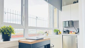 A modern kitchen with large windows, a microwave, a toaster, and a refrigerator. - Top Floor Getaway With Cozy Canopy Bed (Edinburgh)