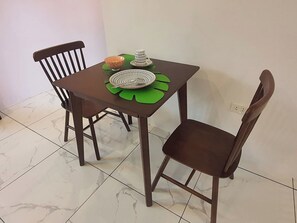 Ruokapöytä, jossa on kaksi tuolia, kulho ja kuppi vihreän aluslakanan päällä.