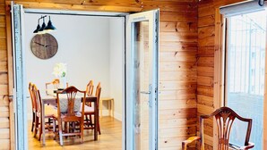 A wooden cabin interior with a dining area, a clock on the wall, and a window with blinds. - Top Floor Apartment with Castle Views (Edinburgh)