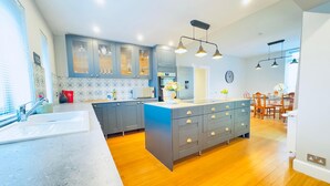 A modern kitchen with grey cabinets, a central island, and a dining area with wooden chairs. - Top Floor Apartment with Castle Views (Edinburgh)