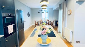 A modern kitchen with a central island, a dining area with a table and chairs, and a living space with a sofa and a coffee table. - Top Floor Apartment with Castle Views (Edinburgh)