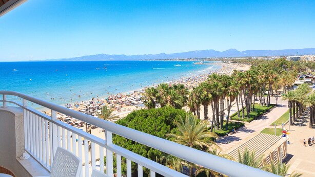 A beach with palm trees, a clear blue sky, and a view of the ocean. - Stunning views, 2-bedroom apartment, Salou centre UHC SANTILLANA 239 (Salou)