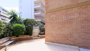 A courtyard with a bench, a brick wall with a sign, and a building in the background. - Stunning views, 2-bedroom apartment, Salou centre UHC SANTILLANA 239 (Salou)