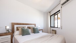 A neatly arranged bedroom with a wooden headboard, a white bedspread, and two bedside lamps. - Stunning views, 2-bedroom apartment, Salou centre UHC SANTILLANA 239 (Salou)