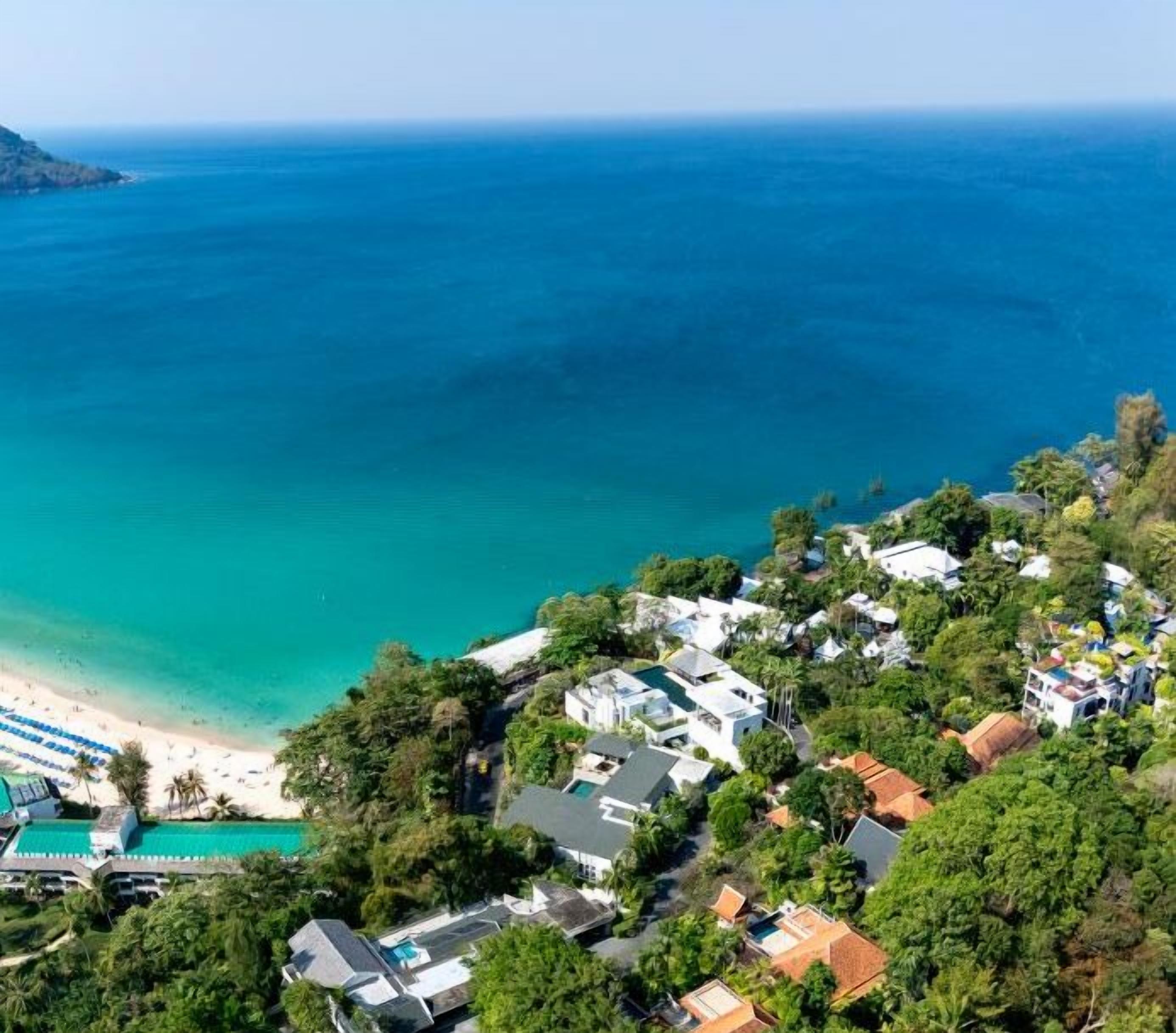 Uma área residencial costeira com casas, uma praia e vista clara para o oceano.