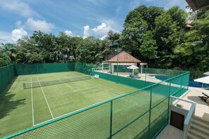 A tennis court with a net, surrounded by a green fence. There is a small pavilion with a tiled roof and a bench. - Katamanda 1Bedrooms Apartment near Kata Beach (Karon)