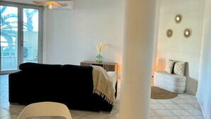 Ein modernes Wohnzimmer mit einem schwarzen Sofa, einem Holzespeisetisch mit Tellern und einem weißen Sessel.