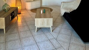 Ein Wohnzimmer mit Couch, Holztisch, Stehlampe und Wanddekoration.