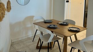 Ein Essbereich mit einem Holztisch, weißen Stühlen und zwei an der Wand befestigten Spiegeln.