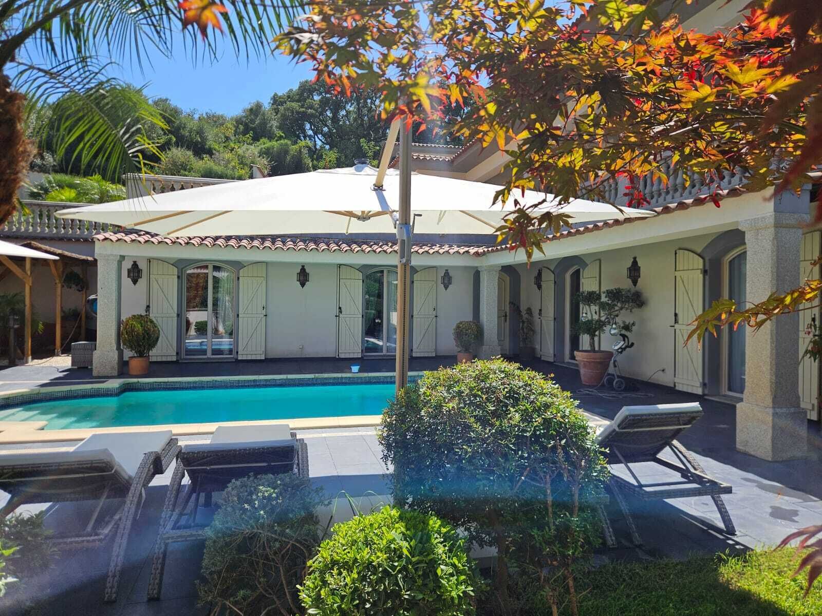 Ein Poolbereich mit überdachter Terrasse und Liegestühlen.