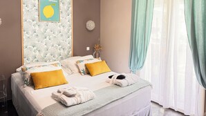 A neatly arranged bedroom with a bed, pillows, a towel, a decorative wall piece, and a window with curtains.
