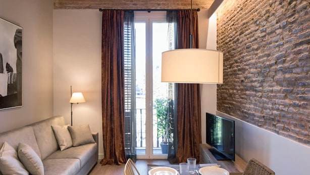 A modern living room with a sofa, dining table, and TV. - Pau Claris Design Apt. Next to Paseo de Gracia (Barcelona)