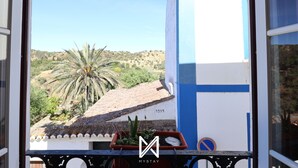 A balcony with a view of a palm tree and a building with the number 1919. - MyStay - A Casa do Visconde (Mertola)