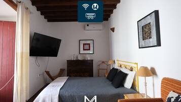 A hotel room with a bed, a TV, a dresser, and a framed picture on the wall.