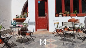 An outdoor patio with a red door, potted plants, and outdoor furniture. - MyStay - A Casa do Visconde (Mertola)