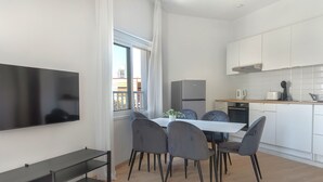Eine moderne Küche mit weißen Schränken, einem Einbauofen und einem Essbereich mit Tisch und Stühlen.