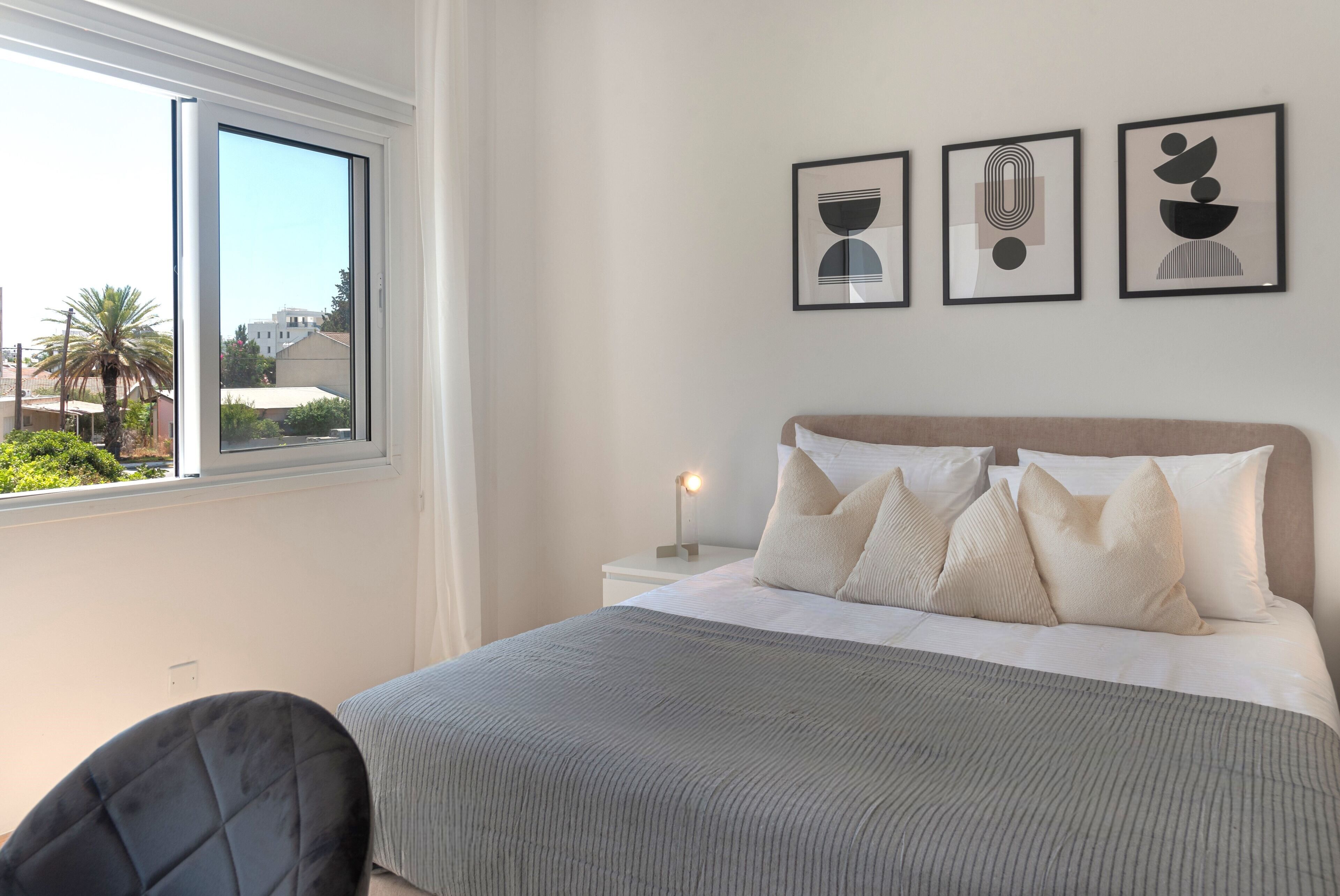 Quarto com cama, mesa de cabeceira, luminária e janela.