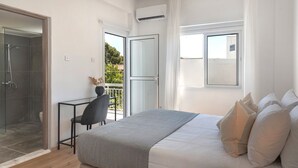 Ein Schlafzimmer mit Bett, Schreibtisch, Stuhl und einer Glasschiebetür, die auf einen Balkon führt.