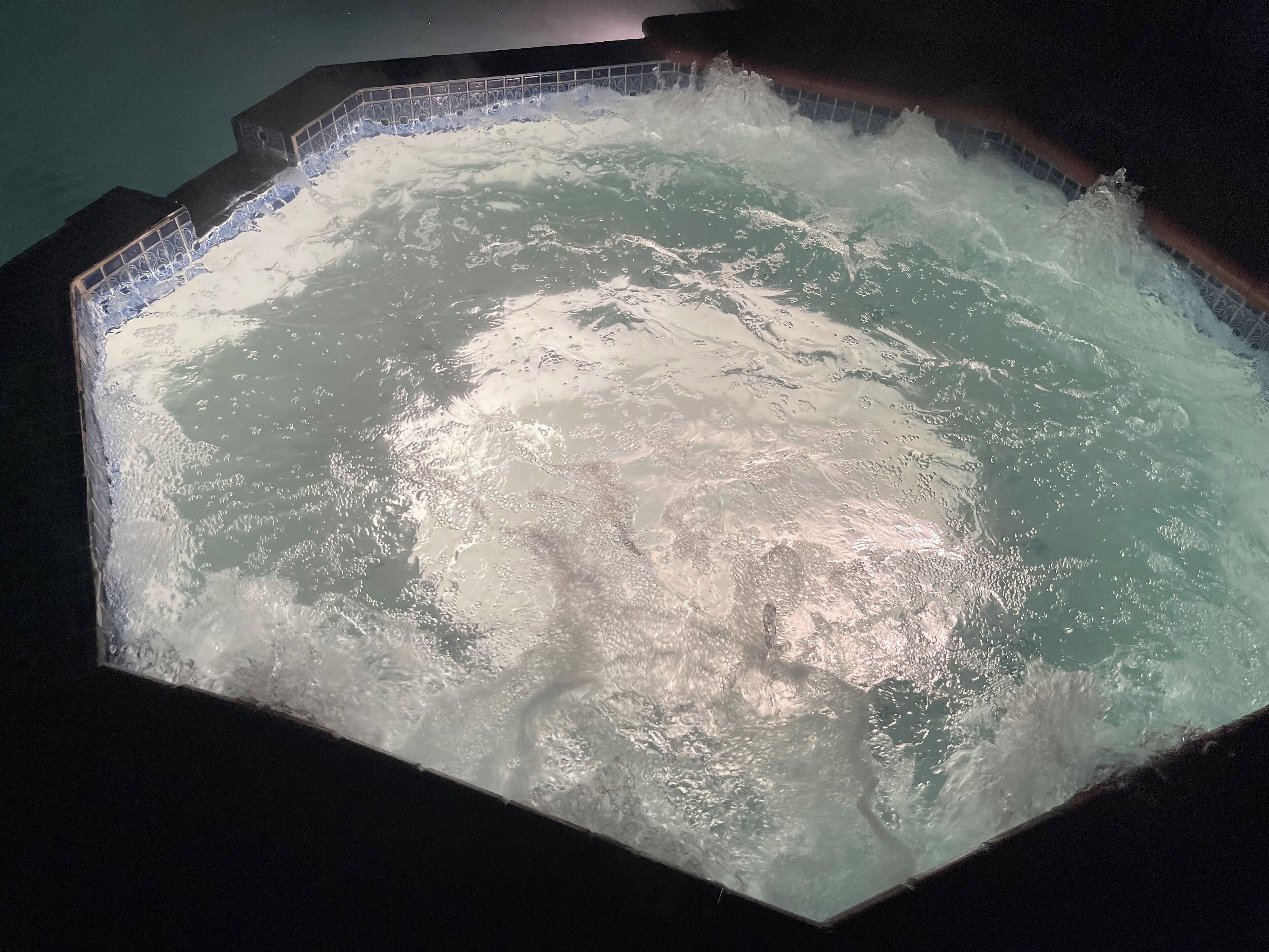 A hot tub with a tiled edge and a visible water jet feature.