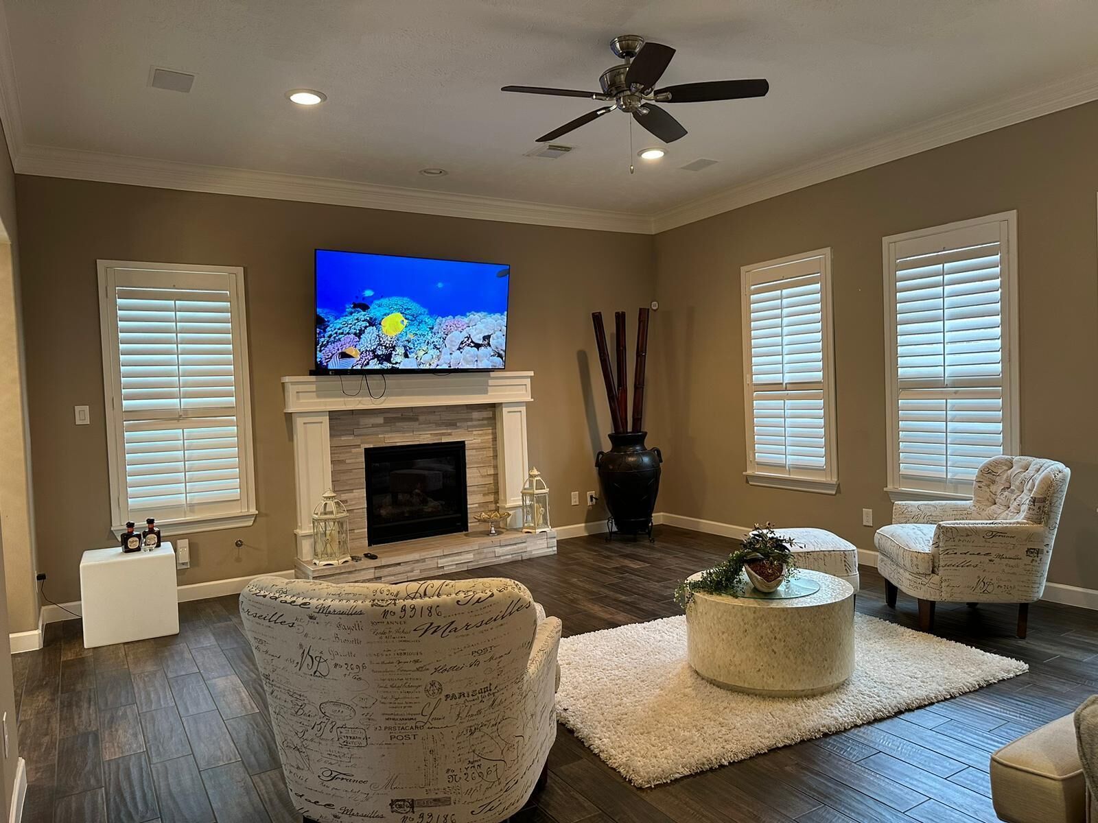 A living room with a flat-screen TV, fireplace, and two armchairs.