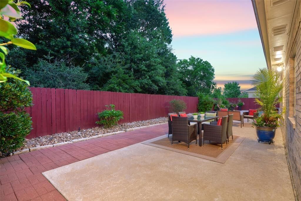 A patio area with a red fence, outdoor furniture, and a potted plant.