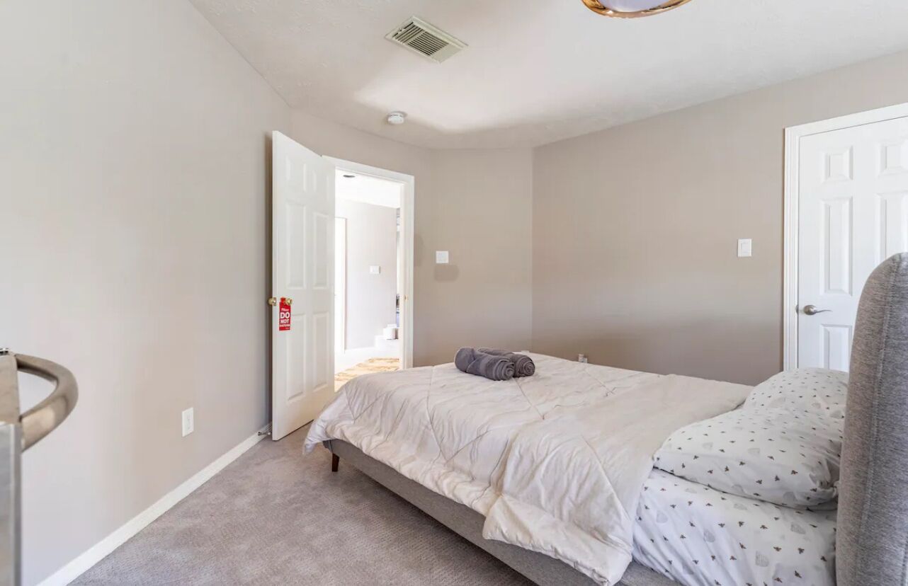 Une chambre à coucher avec un lit, une porte et un couloir visible.