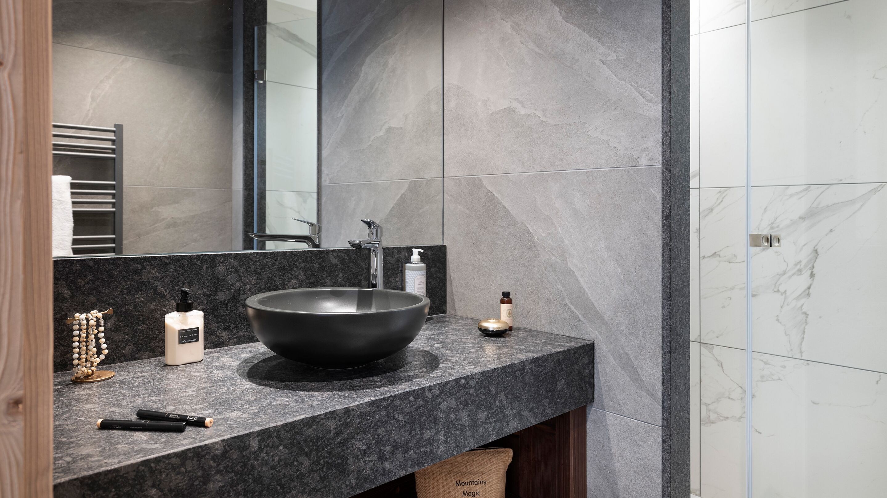 Une salle de bain moderne avec un grand lavabo noir sur pied, un miroir et un porte-serviettes.